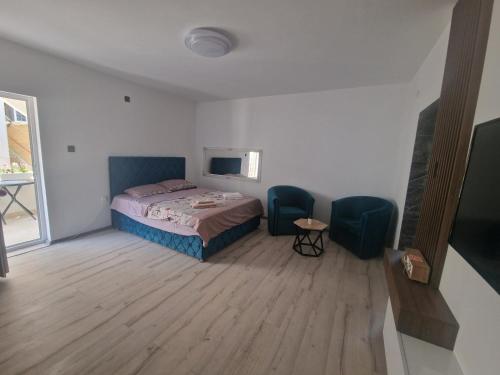 a bedroom with a bed and two blue chairs at Apartmani relax in Leskovac