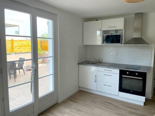 eine Küche mit weißen Geräten und einer Glasschiebetür in der Unterkunft Charmant appartement, T2 50m2, à Biguglia in Biguglia