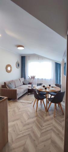 a living room with a table and a couch at Apartamenty Przy Wydmie Dębina in Debina