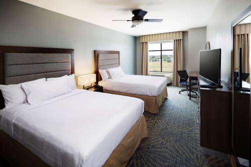 a hotel room with two beds and a flat screen tv at Homewood Suites by Hilton Houston/Katy Mills Mall in Katy