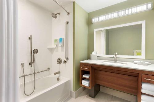 a bathroom with a sink and a tub and a mirror at Home2 Suites by Hilton Milton Ontario in Milton