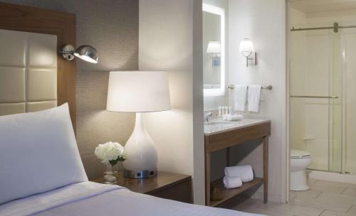 a bedroom with a bed and a bathroom with a sink at Homewood Suites by Hilton Miami Dolphin Mall in Miami