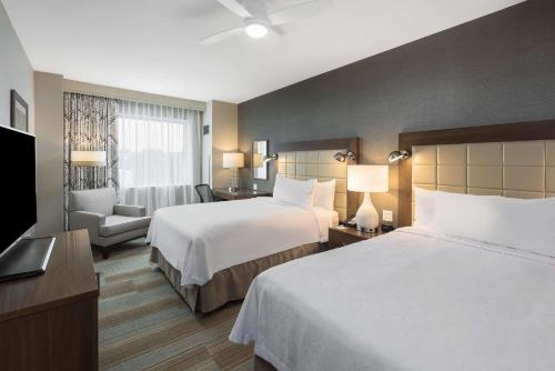 ein Hotelzimmer mit 2 Betten und einem Stuhl in der Unterkunft Homewood Suites by Hilton Miami Dolphin Mall in Miami