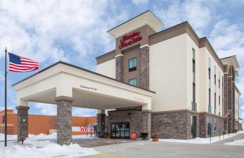 an exterior view of a hotel with an american flag at Hampton Inn & Suites Sioux City South, IA in Sioux City