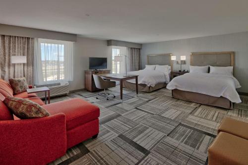 Habitación de hotel con 2 camas y sofá rojo en Hampton Inn & Suites Artesia, en Artesia