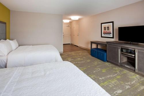 a hotel room with two beds and a flat screen tv at Hampton Inn & Suites Sioux City South, IA in Sioux City