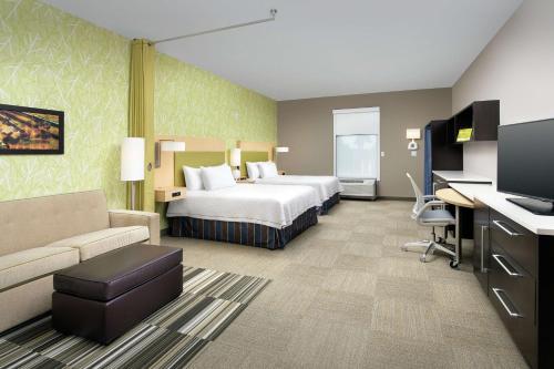 レイク・シティにあるHome2 Suites by Hilton Lake Cityのベッドとソファ付きのホテルルーム