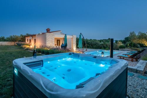 uma banheira de hidromassagem no quintal de uma casa à noite em Villa Silentio em Marčana