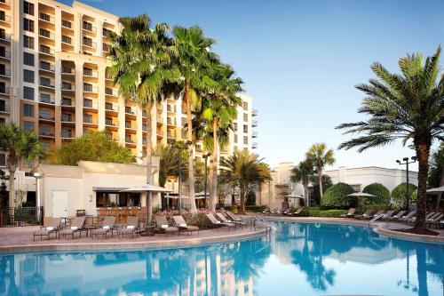 einen Pool mit Stühlen und Palmen vor einem Hotel in der Unterkunft Hilton Grand Vacations Club Las Palmeras Orlando in Orlando