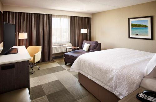 um quarto de hotel com uma cama e uma cadeira e uma janela em Hampton Inn by Hilton Sarnia/Point Edward em Point Edward