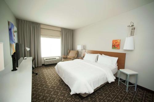 Habitación de hotel con cama blanca y silla en Hilton Garden Inn San Antonio-Live Oak Conference Center, en San Antonio