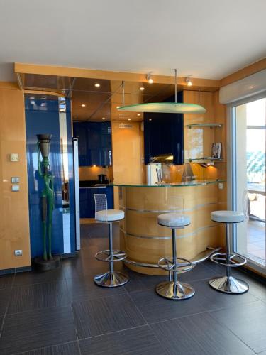 une cuisine avec trois tabourets de bar devant un comptoir dans l'établissement Duplex Alsace Lorraine, jolie appartement, à Nice
