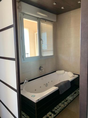 une baignoire dans une salle de bain avec une fenêtre dans l'établissement Duplex Alsace Lorraine, jolie appartement, à Nice