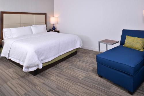 a bedroom with a bed and a blue chair at Hampton Inn & Suites Ann Arbor West in Ann Arbor