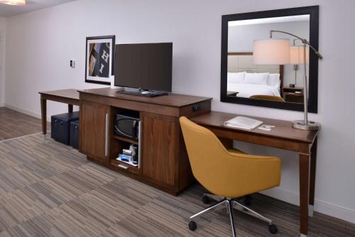 a desk with a television and a chair in a hotel room at Hampton Inn & Suites Ann Arbor West in Ann Arbor