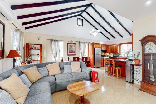 a living room with a gray couch and a kitchen at The Pine Tree Villa in San Ignacio