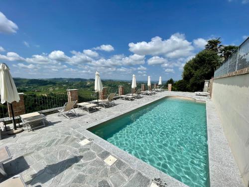 una piscina con tumbonas y sombrillas en Villa Incanto Apartments, en Treiso