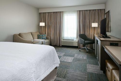 Habitación de hotel con cama, sofá y TV en Hampton Inn & Suites Mason City, IA, en Mason City