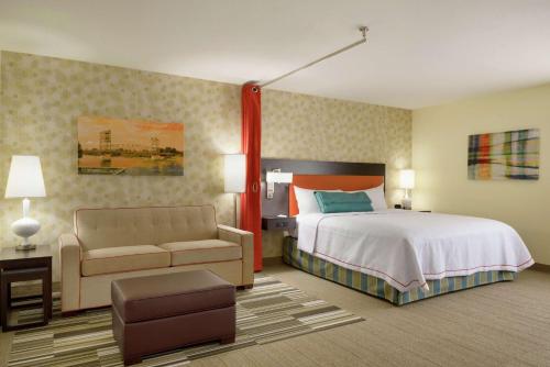 アレクサンドリアにあるHome2 Suites by Hilton Alexandriaのベッドとソファ付きの広いホテルルームです。