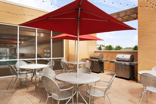 a patio with tables and chairs and a red umbrella at Home2 Suites by Hilton Milwaukee Brookfield in Waukesha