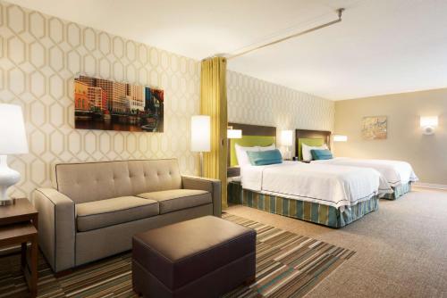 ワカシャーにあるHome2 Suites by Hilton Milwaukee Brookfieldのベッドとソファ付きのホテルルーム