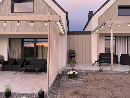 a patio with black chairs and a pergola at Apartamenty Lawendowy Zakątek in Władysławowo