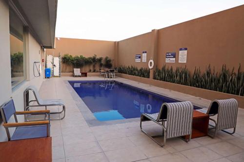 a swimming pool in a building with chairs and a table at Hampton Inn by Hilton Irapuato in Irapuato