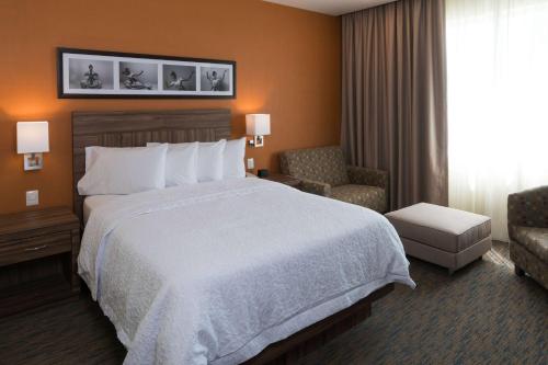 um quarto de hotel com uma cama grande e uma cadeira em Hampton Inn by Hilton Irapuato em Irapuato