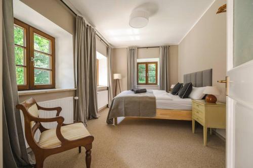 a bedroom with a bed and a chair and windows at Mountain Chalet on Gut Buchwies in Oberau