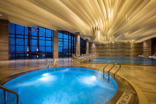 a swimming pool in a hotel with a ceiling at Hilton Wuhan Yangtze Riverside in Wuhan