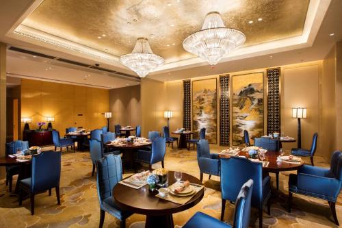 uma sala de jantar com mesas, cadeiras e lustres em Hilton Wuhan Yangtze Riverside em Wuhan