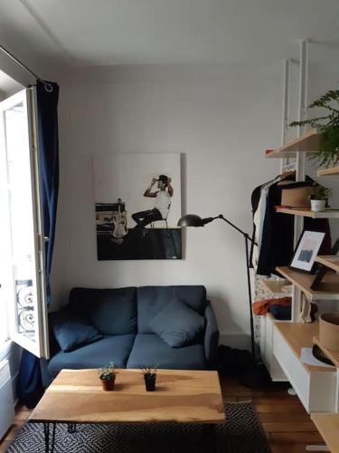 uma sala de estar com um sofá azul e uma mesa em Paris: Appartement Batignolles em Paris