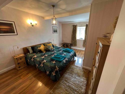 a bedroom with a bed with a green comforter at 17th Century Cottage, Log Burner & Hidden Garden in Oakworth