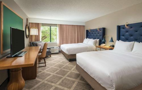 a hotel room with two beds and a desk at DoubleTree by Hilton Gainesville in Gainesville