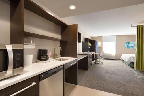 a kitchen with a sink and a room with a bed at Home2 Suites by Hilton Billings in Billings