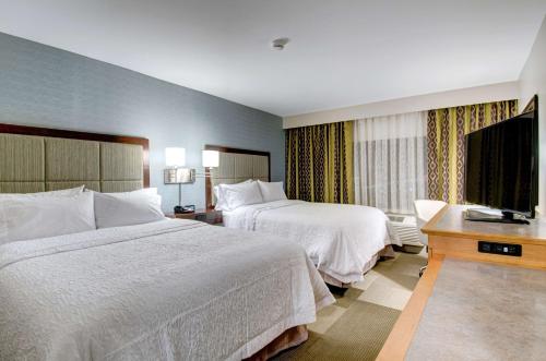a hotel room with two beds and a flat screen tv at Hampton Inn Boston - Westborough in Westborough