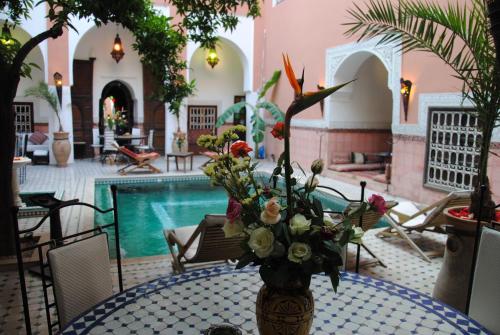 a vase of flowers sitting on a table next to a pool at Riad Barroko in Marrakech