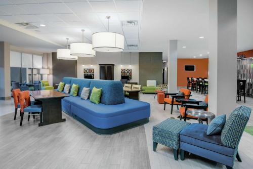 a lobby with a blue couch and tables and chairs at Home2 Suites By Hilton Austin Airport in Austin