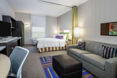 Home2 Suites By Hilton Austin Airport في أوستن: غرفة في الفندق مع أريكة وسرير