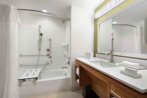 a bathroom with a sink and a tub and a mirror at Home2 Suites By Hilton Middleburg Heights Cleveland in Middleburg Heights