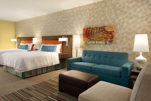 a hotel room with a bed and a blue couch at Home2 Suites By Hilton Middleburg Heights Cleveland in Middleburg Heights