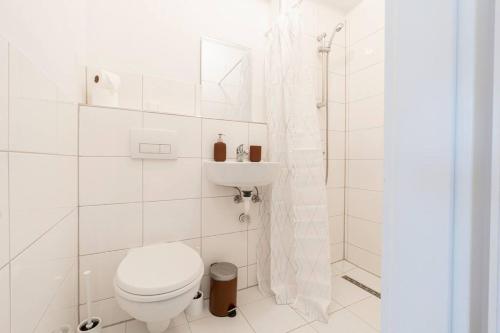 Baño blanco con aseo y lavamanos en Stilvolles Apartment für 4 Pers. en Bremen