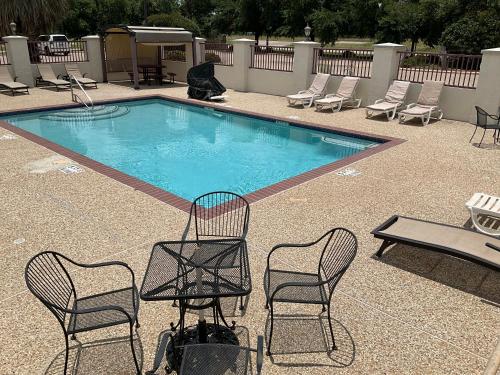 a pool with two chairs and a table and chairsitures at Budget Host Inn and Suites Cameron in Cameron