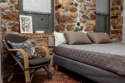 uma cama e uma cadeira num quarto com uma parede de pedra em Barhouse em Katsíngrion