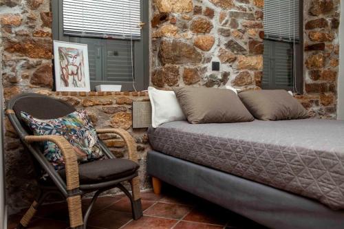 a bed and a chair in a room with a stone wall at Barhouse in Katsíngrion