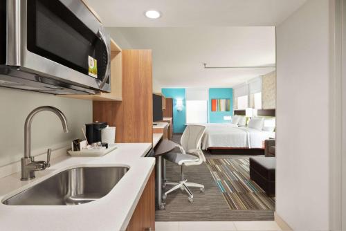 eine Küche mit einem Waschbecken und ein Zimmer mit einem Bett in der Unterkunft Home2 Suites by Hilton Woodbridge Potomac Mills in Woodbridge