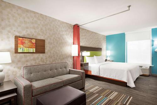 a hotel room with a bed and a couch at Home2 Suites by Hilton Woodbridge Potomac Mills in Woodbridge