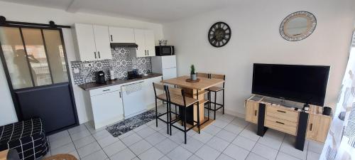 une cuisine avec une télévision, une table et un comptoir dans l'établissement Charmant Studio climatisé Vue mer à 100m plage du Môle, au Cap d'Agde