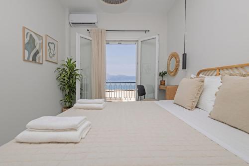 a white bedroom with a large bed with a view of the ocean at La Mer in Agios Rokkos