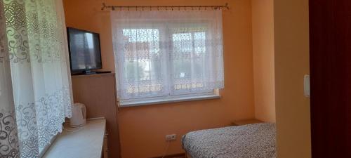 Dormitorio con ventana, cama y TV en Kwatera Mikołajki, en Mikołajki